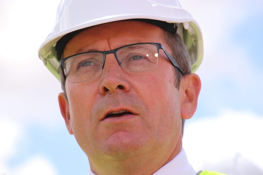 Close-up photo of man wearing reading glasses and a hard hat