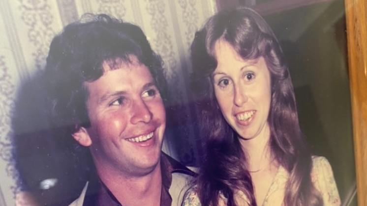 A man and a woman wearing wedding outfits and smiling.