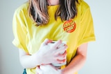 A woman in a yellow tshirt grips two rolls of toilet paper