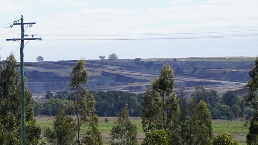 Looking through trees and a powerline to a coal pit at Acland in Southern Queensland