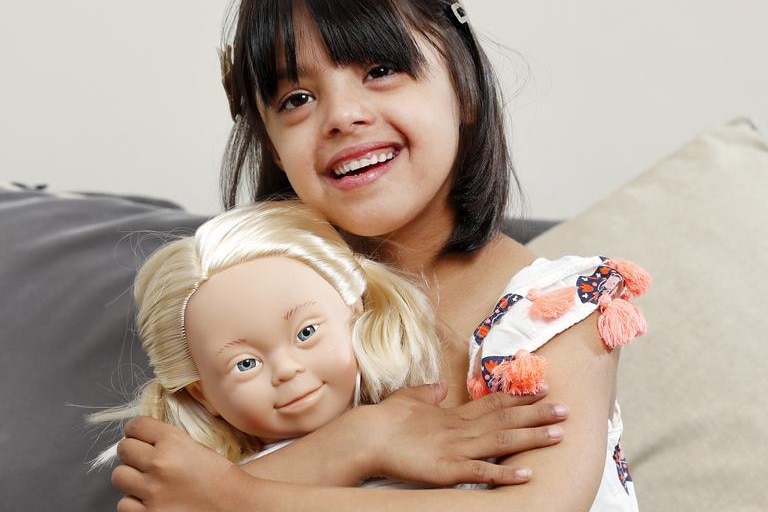 A young girl hugs a childlike doll