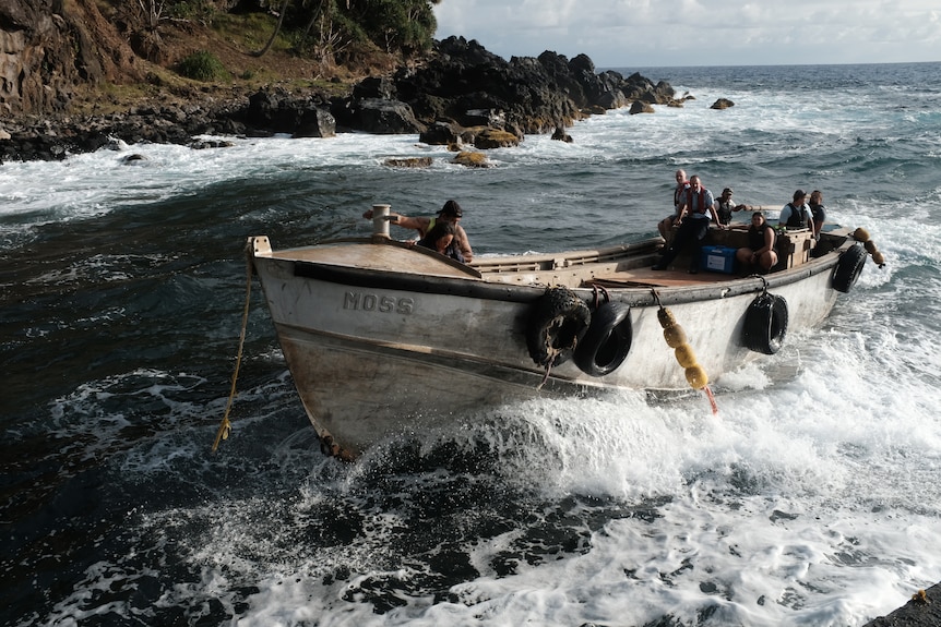 Un canot s'écrase à travers de petites vagues à son arrivée sur l'île. 