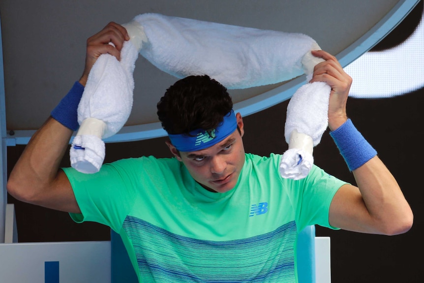 Feeling the heat ... Milos Raonic puts on an ice towel during a break while playing Dustin Brown