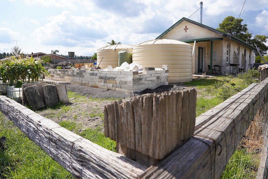 Two large water tanks and a big raised garden bed take up yard space next to a former church building.