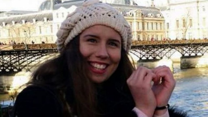 A smiling Masa wearing a white beanie with a European scene behind her.