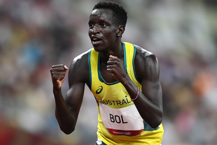 Peter Bol clenches his fists in a yellow Australia singlet.