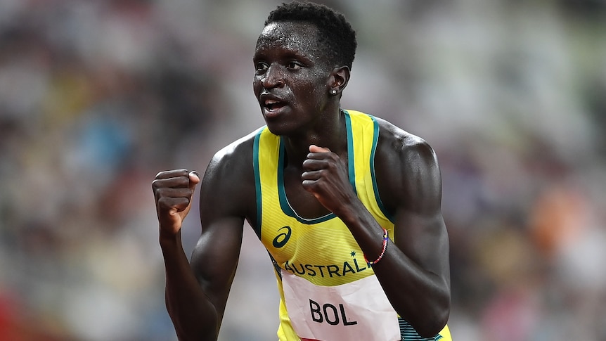 Peter Bol clenches his fists in a yellow Australia singlet.