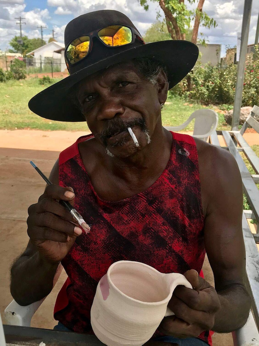 man painting clay mug