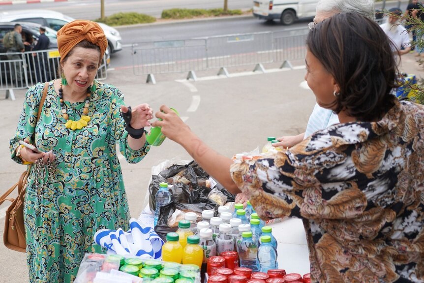 A woman handing another woman a drink