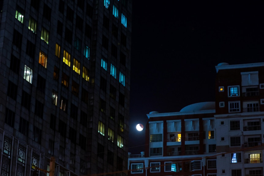 A lunar eclipse is seen in Bangkok, Thailand through office buildings