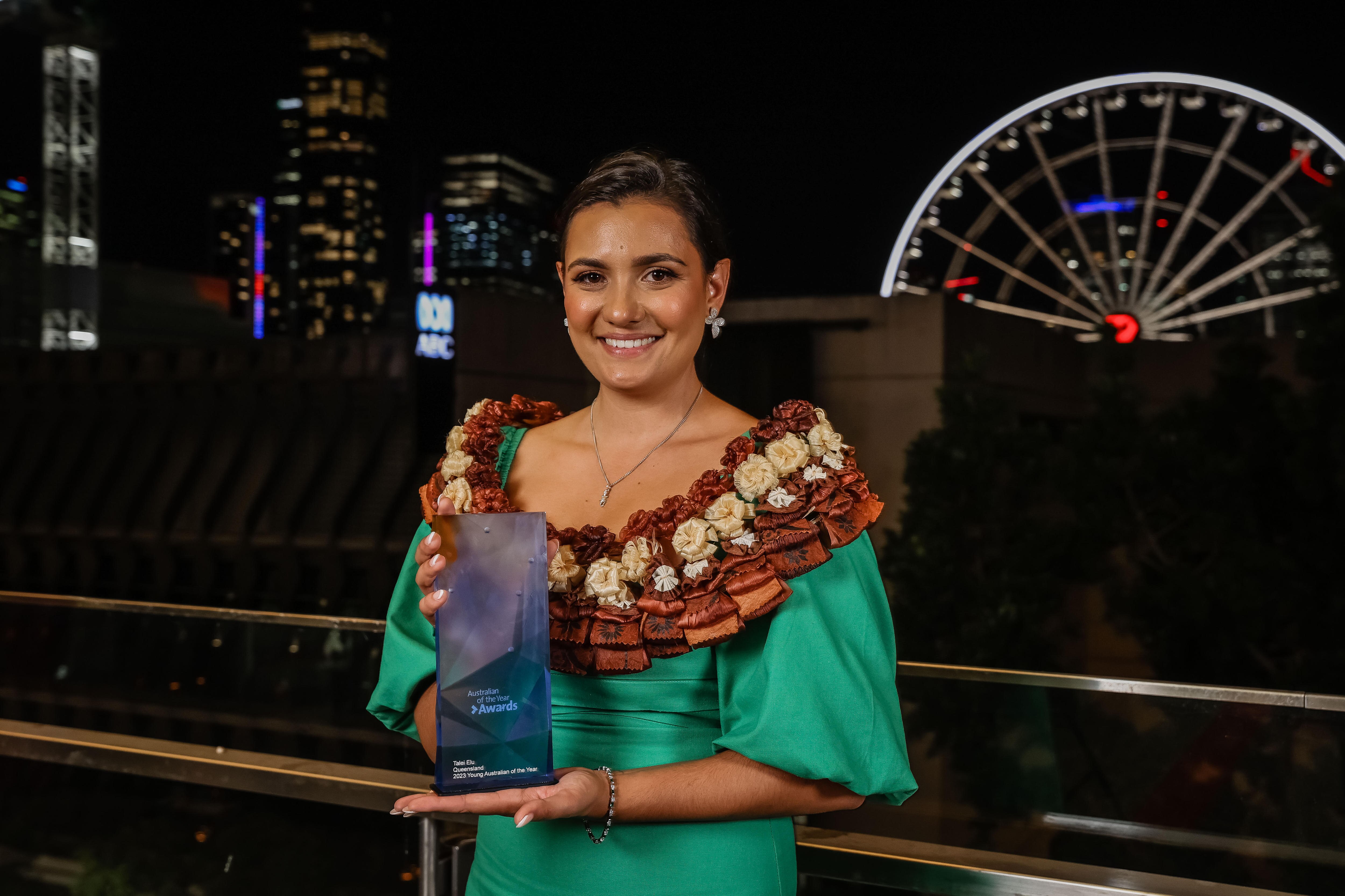 A young woman in traditional dress holding her australian of the year trophy 