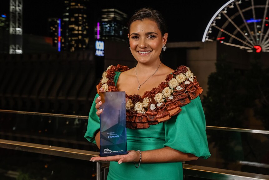 A young woman in traditional dress holding her australian of the year trophy 