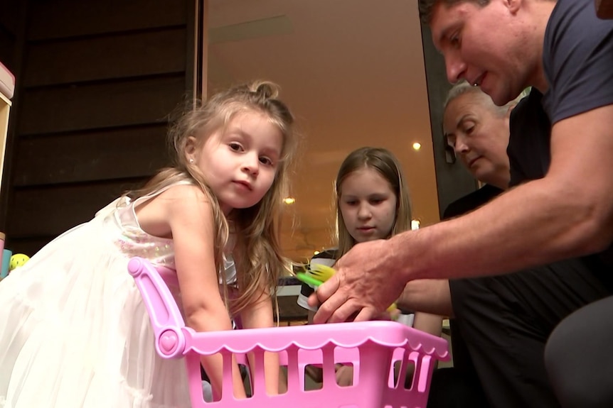 A child plays with toys with her sister and two adults