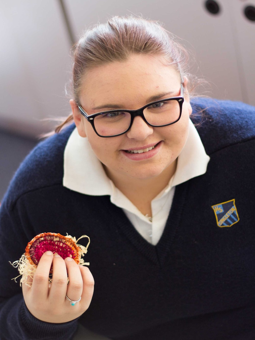 Chelsea Croucher holds a piece of weaving.