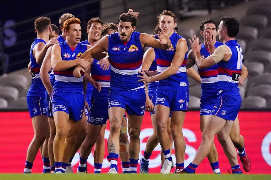 Western Bulldogs AFL players group together as they celebrate a goal against North Melbourne.