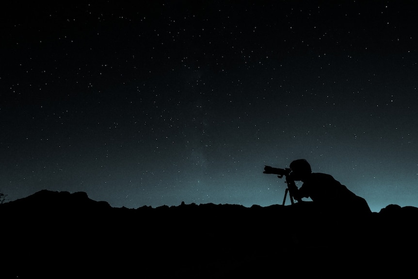 A man looking at the stars with a telescope