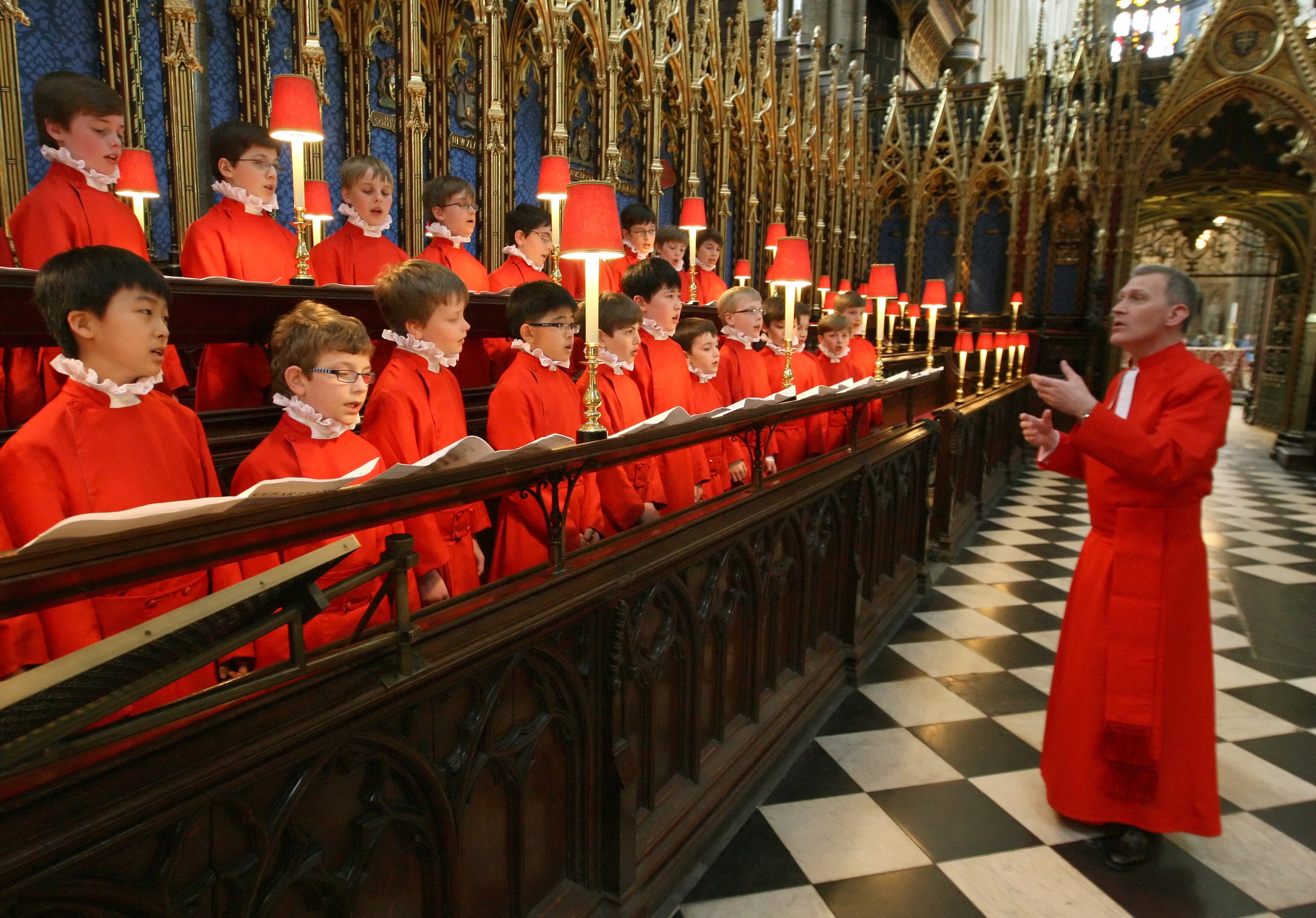 Organist and Master of the Choristers James O&#x27;Donnell conducts the Choir of Westminster Abbey, dressed in red robes.