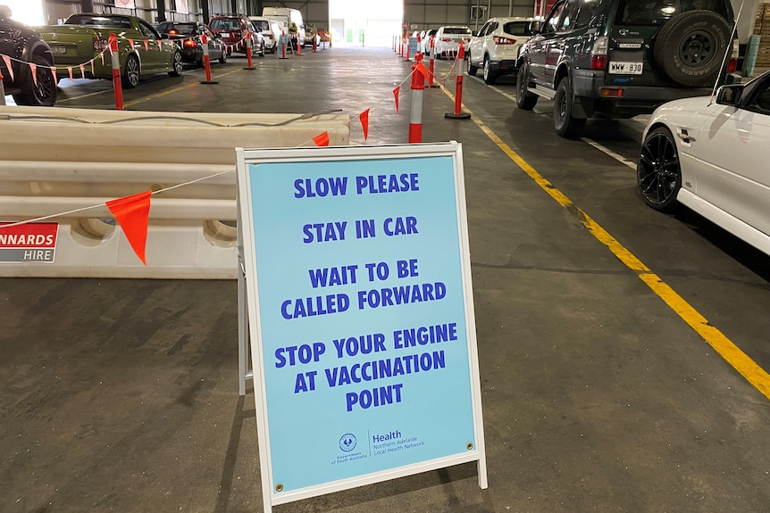 Two lines of queued cars with a sign in the middle directing them where to go