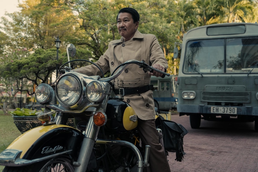 A Vietnamese man in a military uniform rides a motorbike