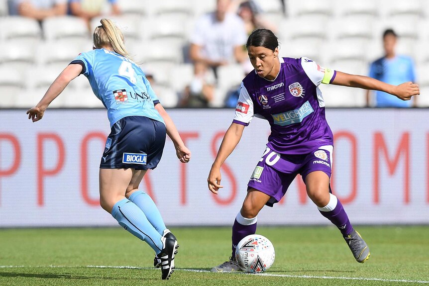 A wide shot of Sam Kerr dribbling the ball towards a defender during the W-League grand final.
