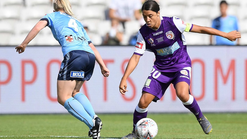 A wide shot of Sam Kerr dribbling the ball towards a defender during the W-League grand final.
