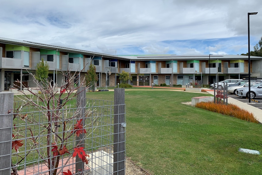 A double story block of flats with a lawn in the foreground