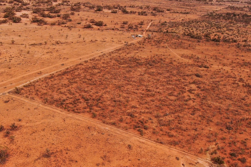 An aerial photo showing a square of red earth with a fence around it