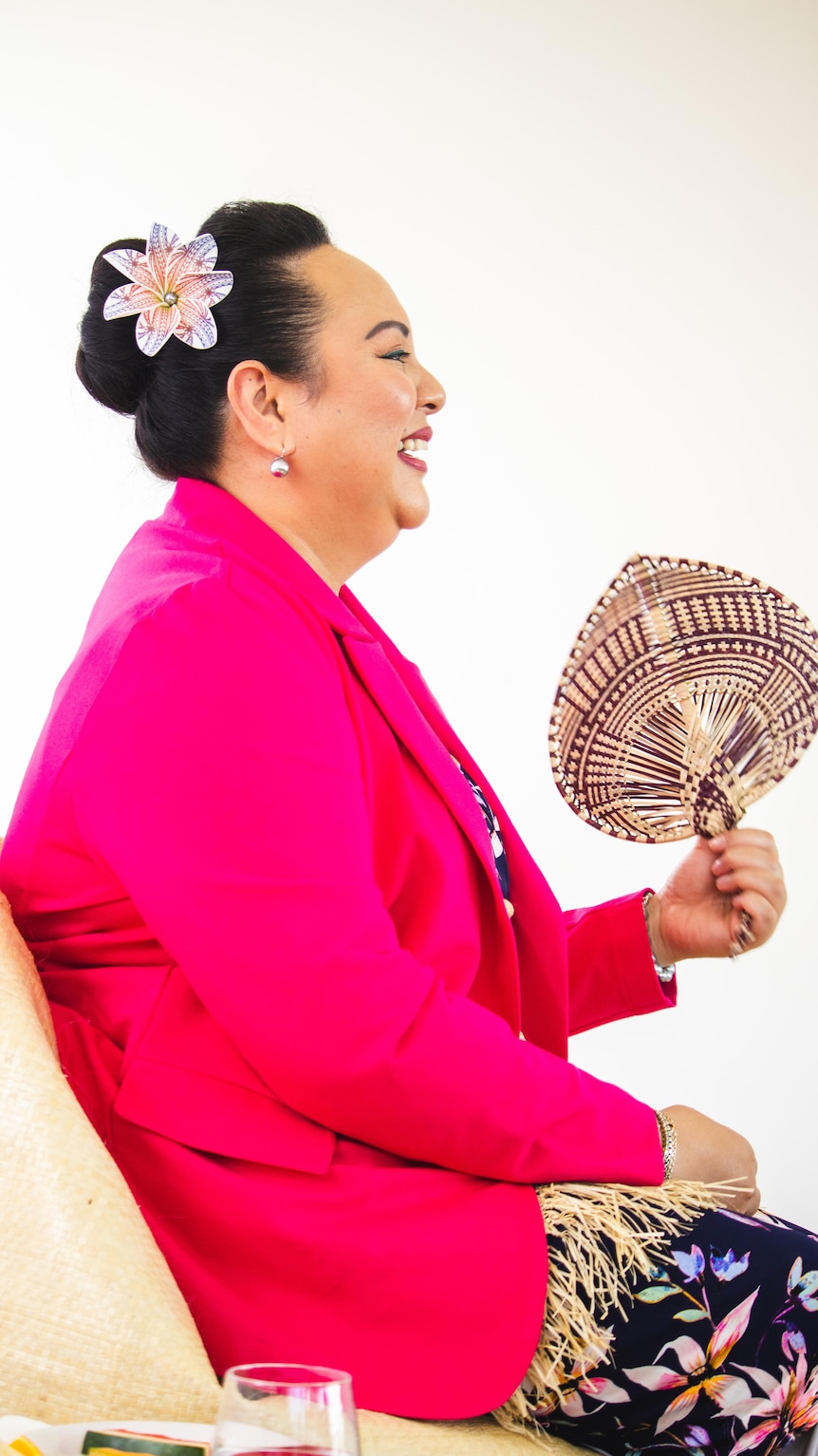 HRH Angelika Latufuipeka Tuku’aho, Princess of Tonga is seated on a chair, smiling and waving a fan