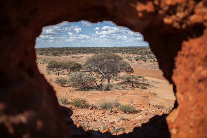 A desert scape as seen through a hole in a rock formation.