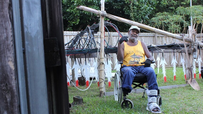 a man in a wheelchair in a backyard with sculpture