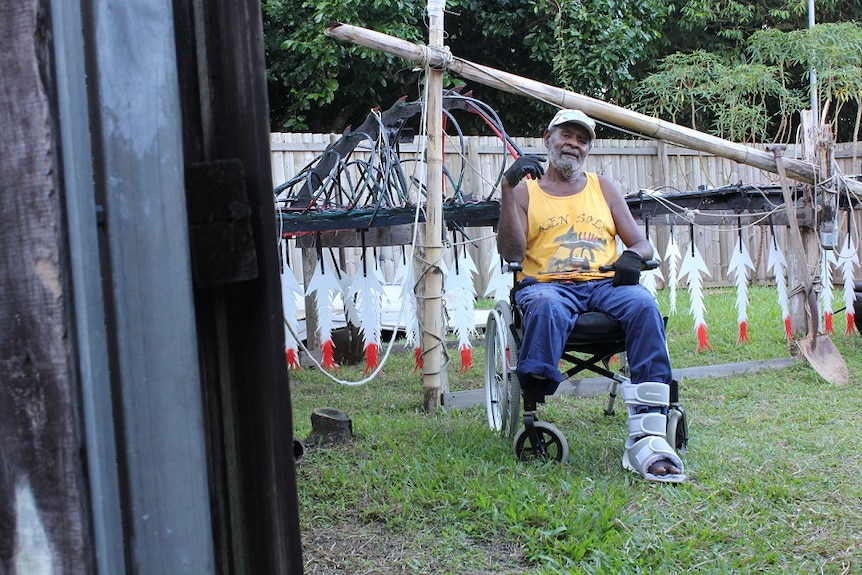 a man in a wheelchair in a backyard with sculpture