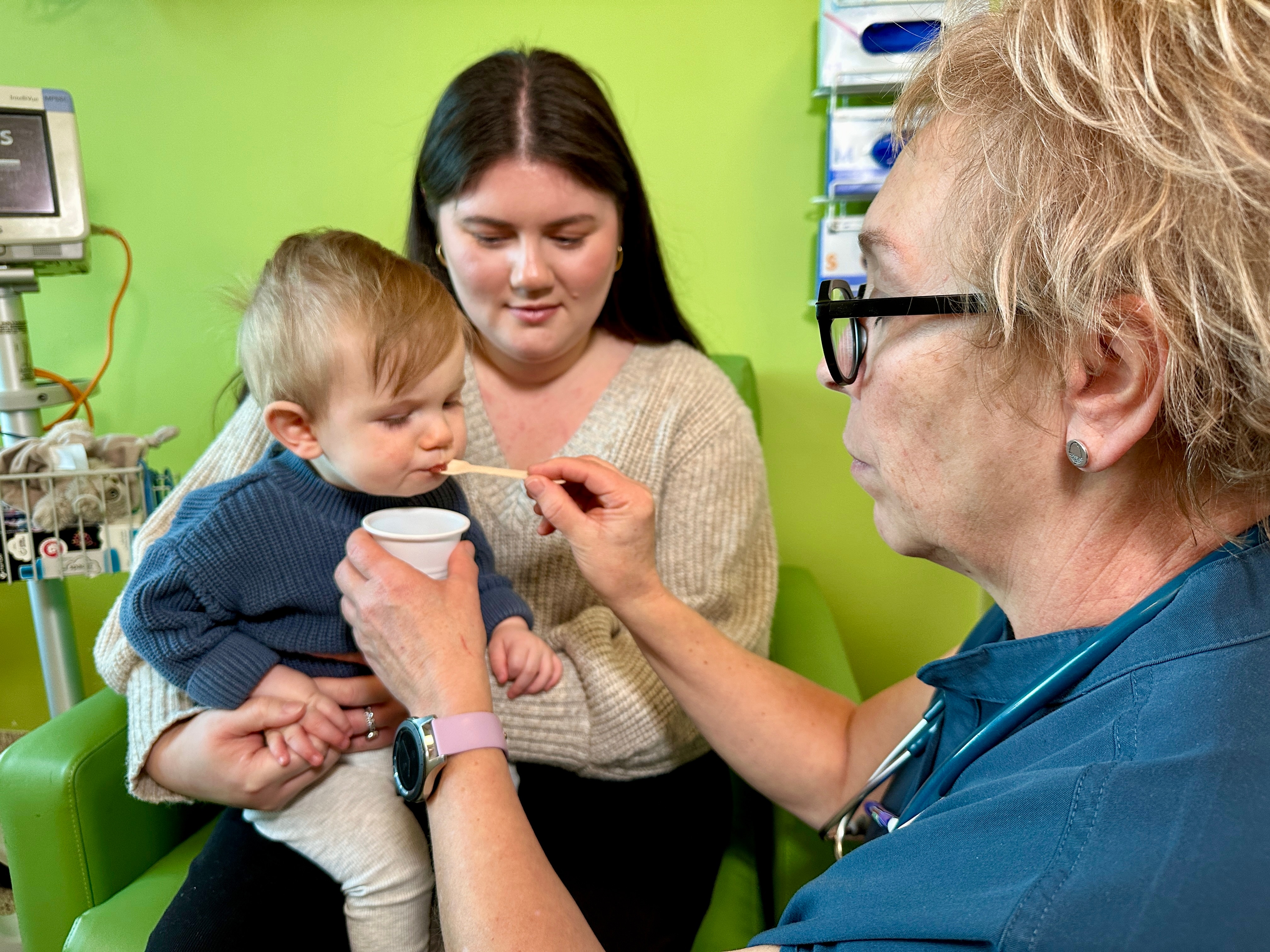 A doctor gives Hunter a spoonful of puree with peanut powder in it. 