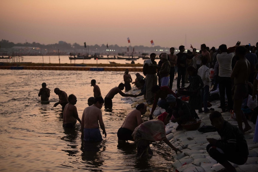 Men bathe where the sacred Ganges and Yamuna rivers meet in India