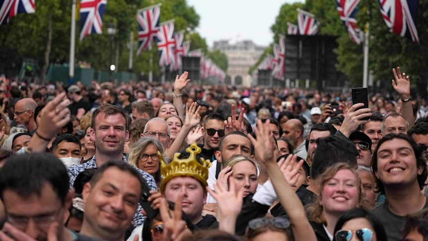 Huge crowds of Royal fans waving British flags fill the Mall near Buckingham Palace.