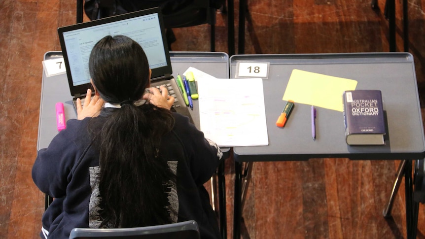 A female student completes her exam using a laptop.