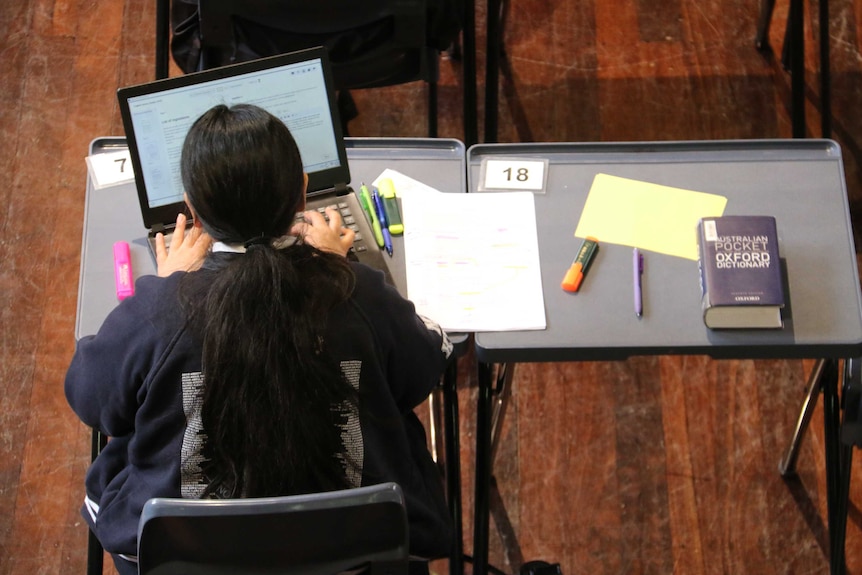 A female student completes her exam using a laptop.