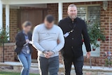 Two men walking away from a house, one face blurred the other man smiling