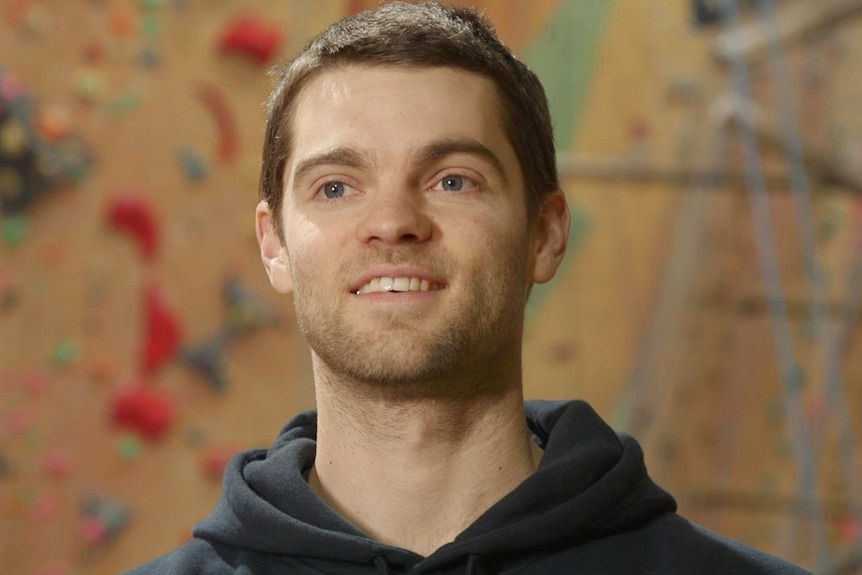 A male climber smiles as he is doing a TV interview.