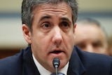 Michael Cohen wearing a blue tie speaking into a microphone.