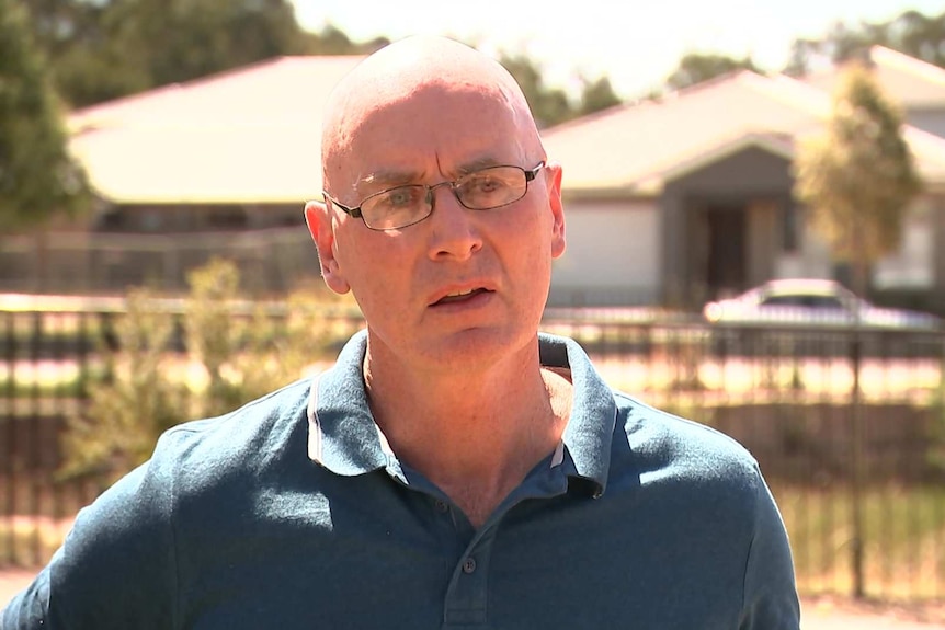 A man with glasses talking outside.