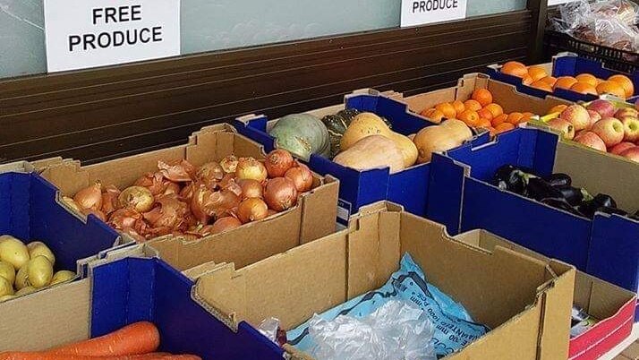 Boxes of carrots, onions, pumpkins and an assortment of fruit line an outside stall beneath a read Salvation Army sign.