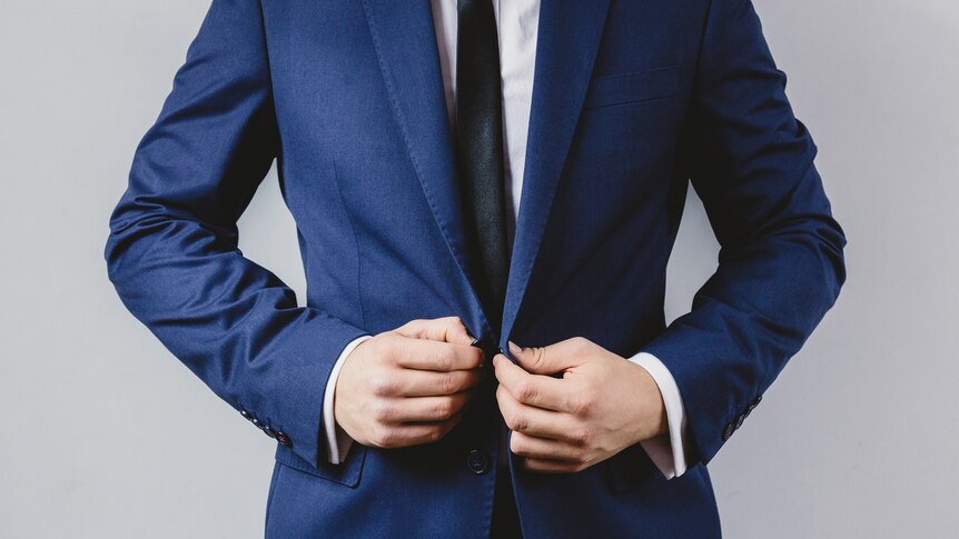 A man stands confidently in a suit.