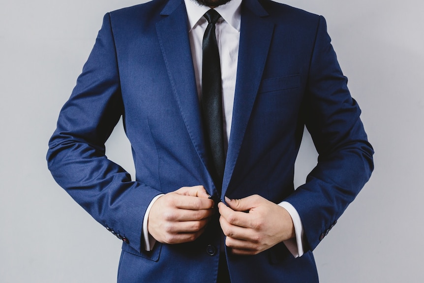 A man stands confidently in a suit.