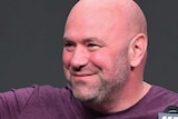 Dana White stands and looks off to one side, holding one hand up with two fingers stretched out