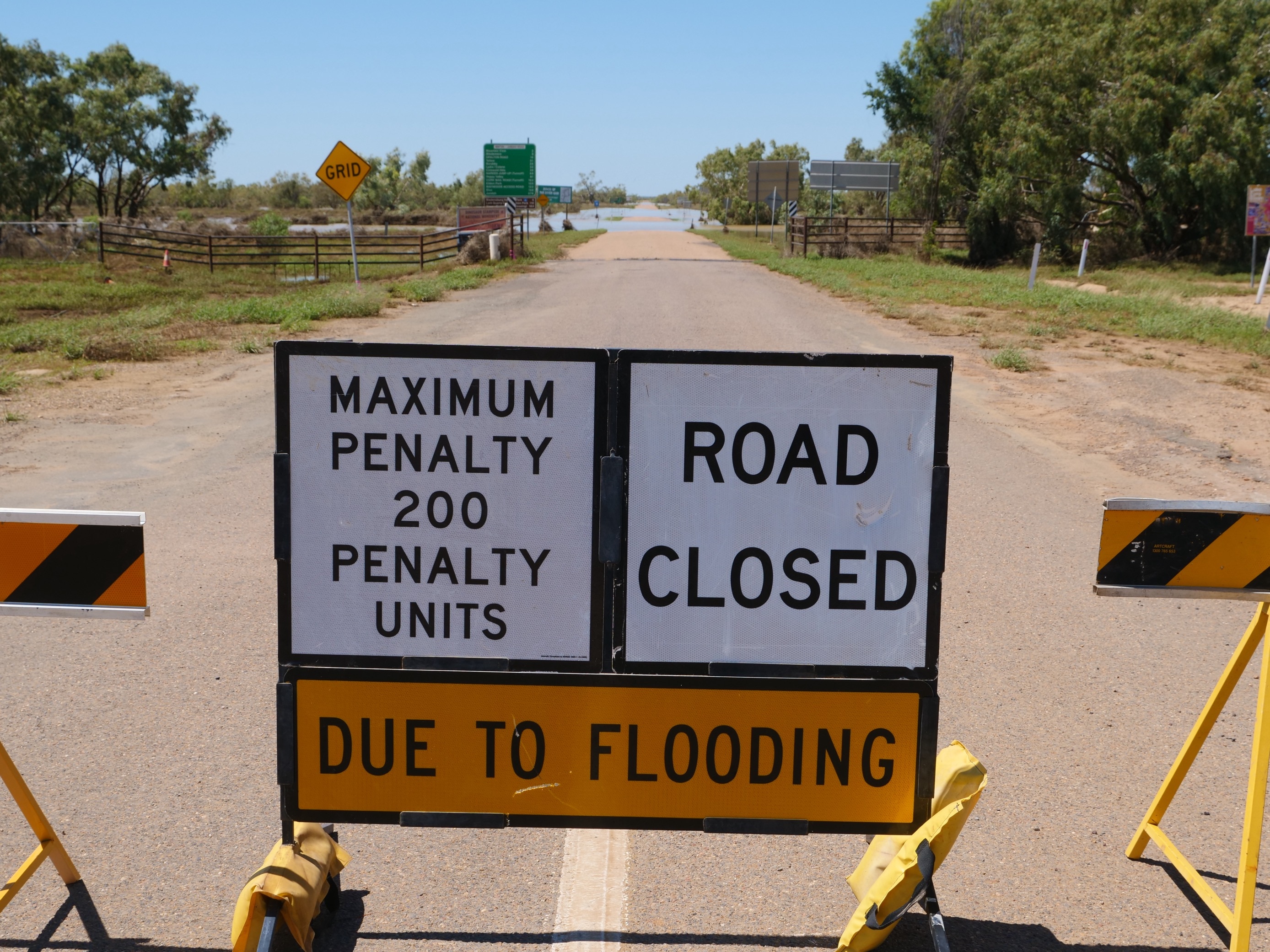 Un cartel de cierre de vía por inundación advierte a los automovilistas que se les impondrá una multa máxima de 200 unidades si continúan más allá de este punto.