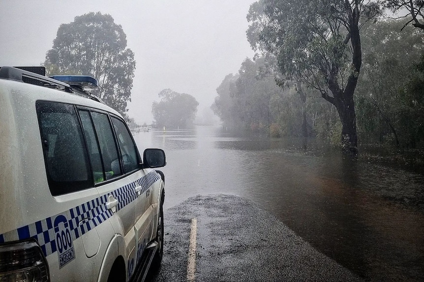 A NSW police car in front of a flooded road