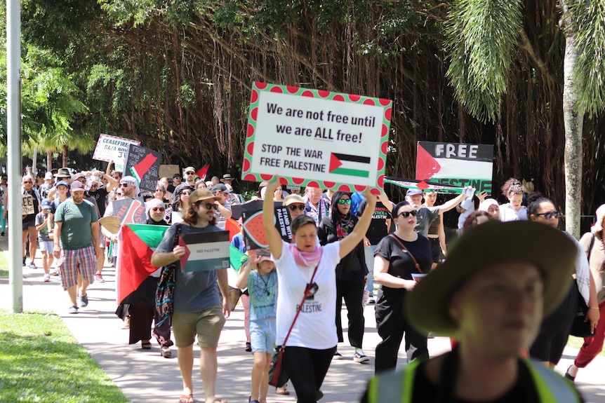 Pro-Palestine protesters holding signs during march in Cairns. 