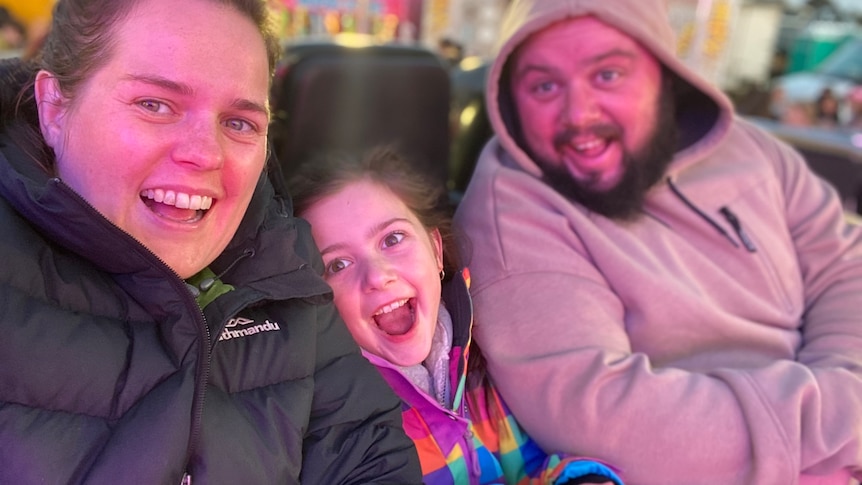 Family photo of woman, man and child smiling happily 