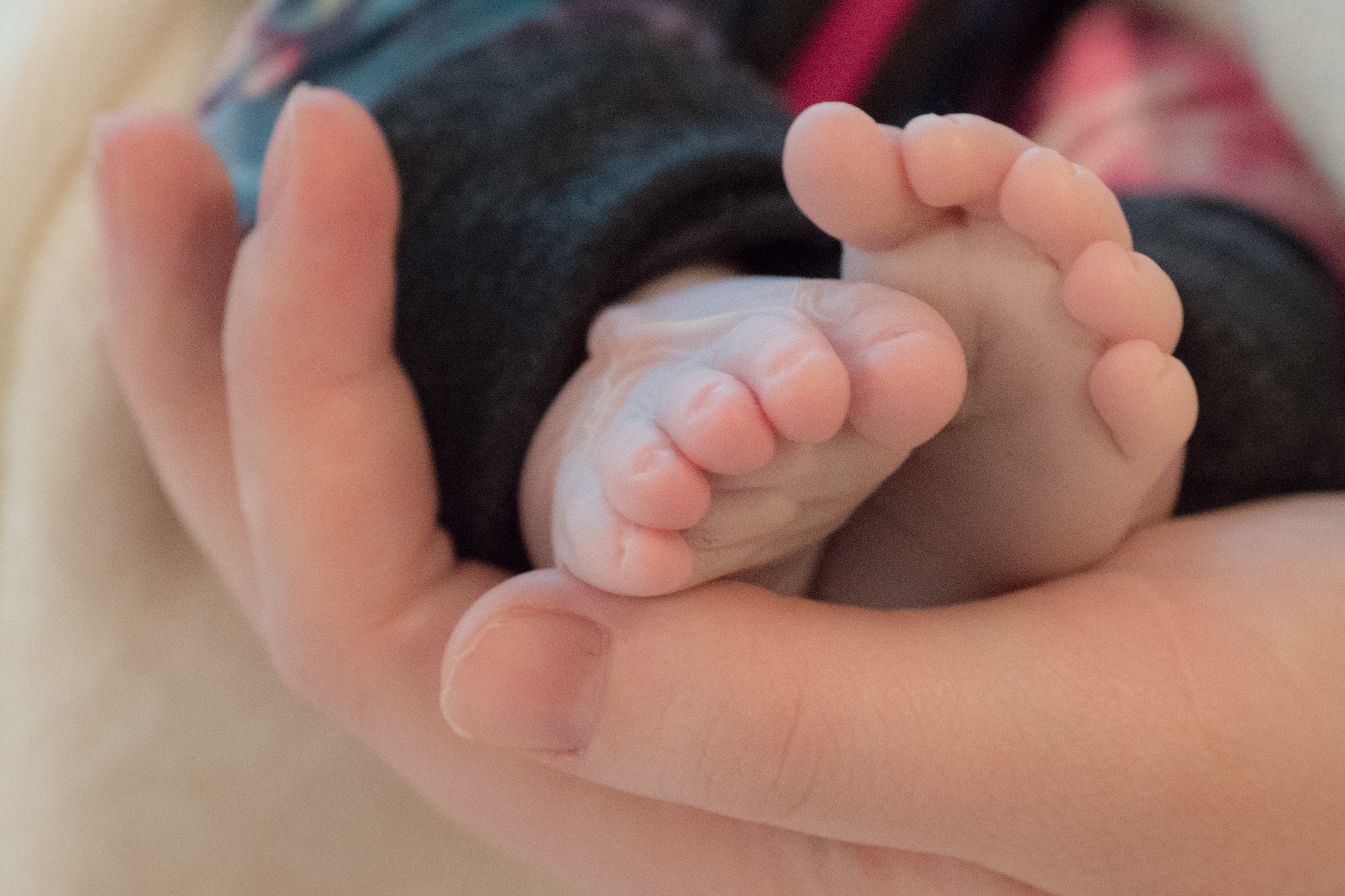 A woman holds the feet of a baby. 
