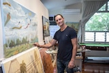 Acclaimed Australian artist Robert Brownhall stands alongside some of his paintings in his studio in Brisbane.